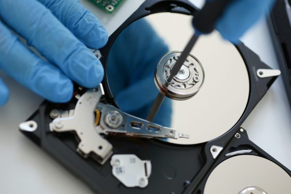Male repairman wearing blue gloves dismantles specialized professional screwdriver hard drive. Performs fault diagnostics and performs urgent repairs recovery of lost data during deletion HDD closeup