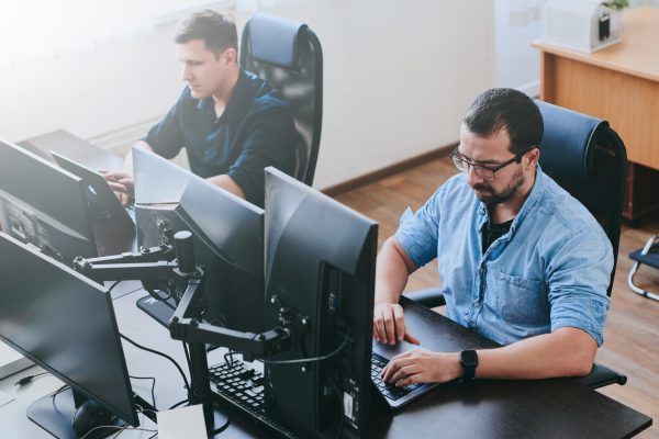 Portrait of two professional male programmers working on computer in diverse offices. Modern IT technologies, development of artificial intelligence, programs, applications and video games concept
